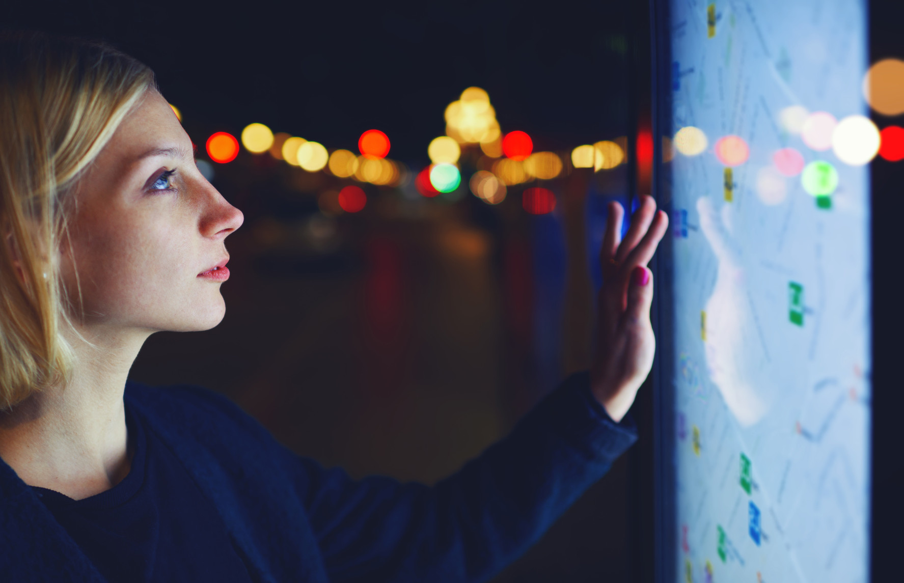 MOOC Summaries - TechniCity - Young female tourist using smart city gadget to get direction in Barcelona central, female in night city standing front big digital screen with city map routes and locations shown on it